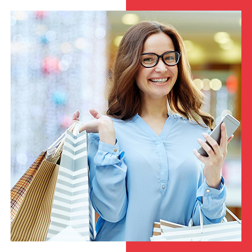 Laughing shopper with smartphone and bags